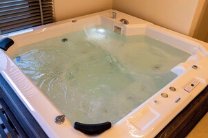 Un jacuzzi con panel de control, un asiento integrado y un ventanal.