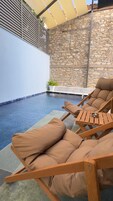 Zona de piscina con sillas de descanso y un muro de piedra.