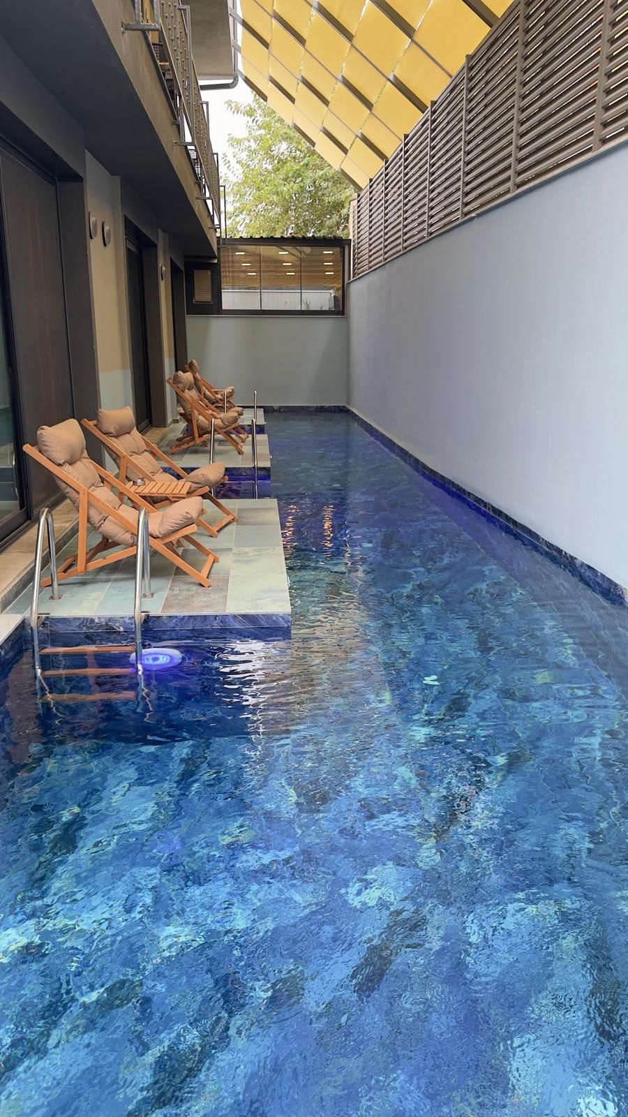 A swimming pool with lounge chairs and a covered area.