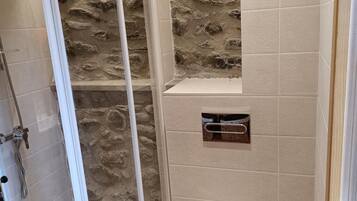 Une salle de bain avec une douche, des toilettes et une étagère intégrée.