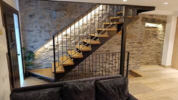 A modern staircase with wooden steps and metal railings, leading to a stone wall.