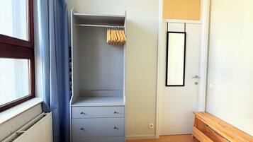 A bedroom with a bed, a wardrobe, a radiator, and a door with a mirror.