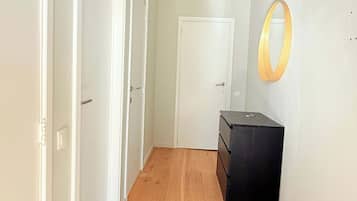 A hallway with wooden flooring, white walls, and a black storage unit.