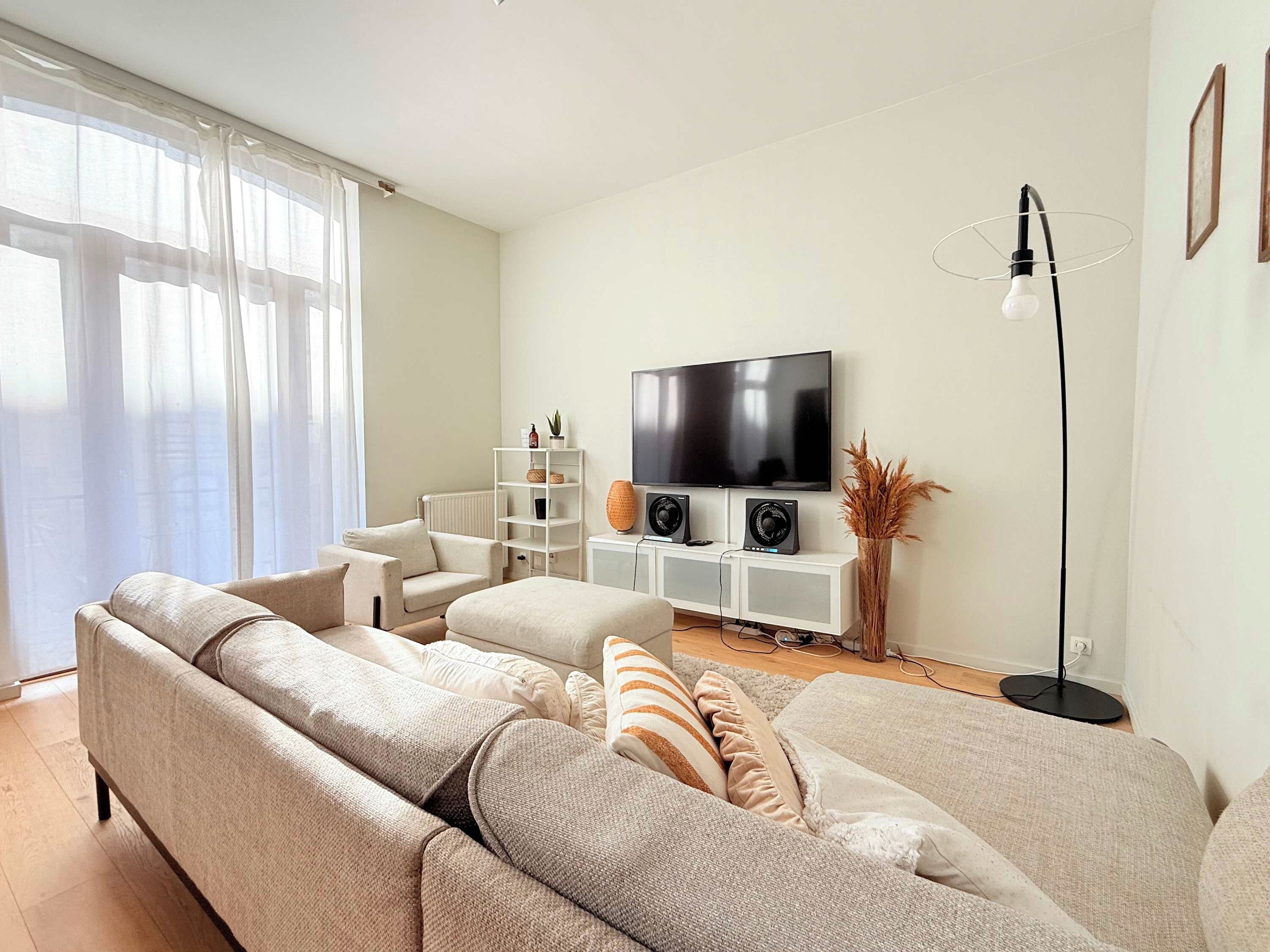 A living room with a large sofa, a television, and a floor lamp.