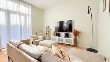 A living room with a large sofa, a television, and a floor lamp.