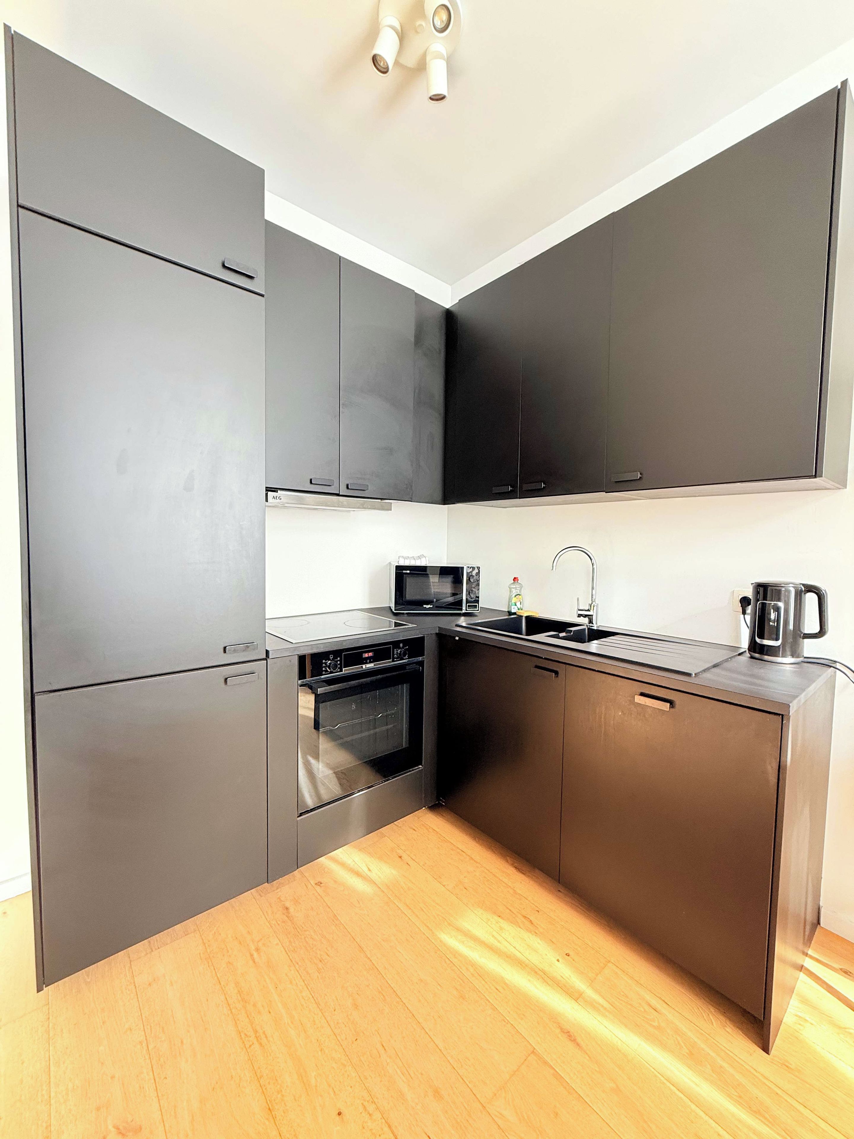 A compact kitchen with a microwave, oven, and sink.