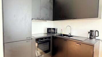 A compact kitchen with a microwave, oven, and sink.