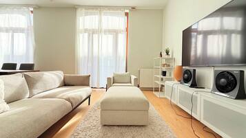 Een moderne woonkamer met een bank, een poef en een flatscreen televisie.