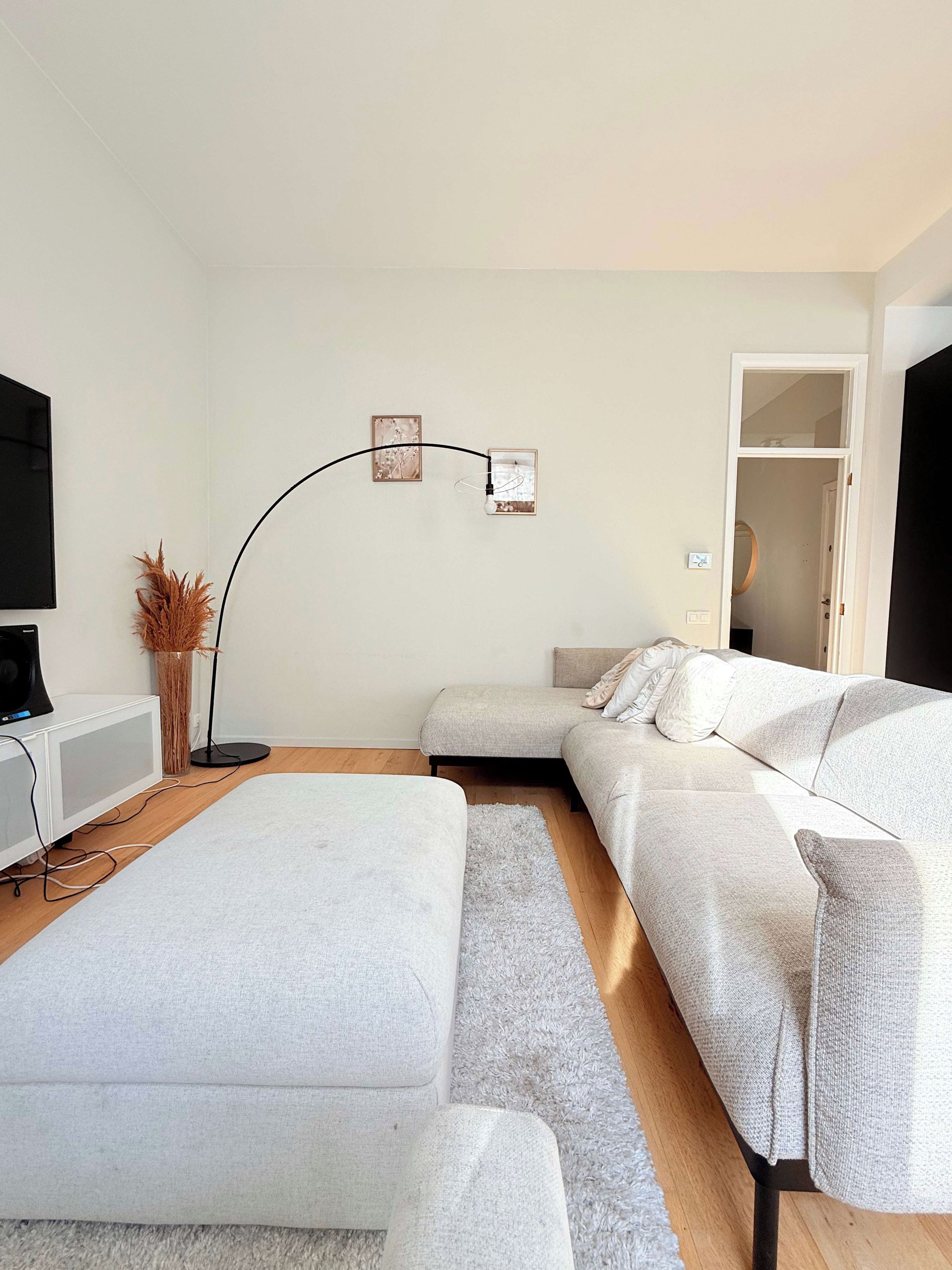 A modern living room with a sofa, a flat-screen TV, and a floor lamp.