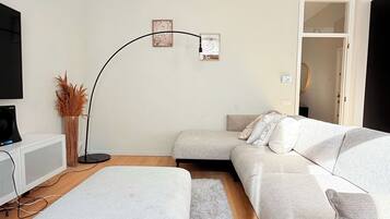 A modern living room with a sofa, a flat-screen TV, and a floor lamp.
