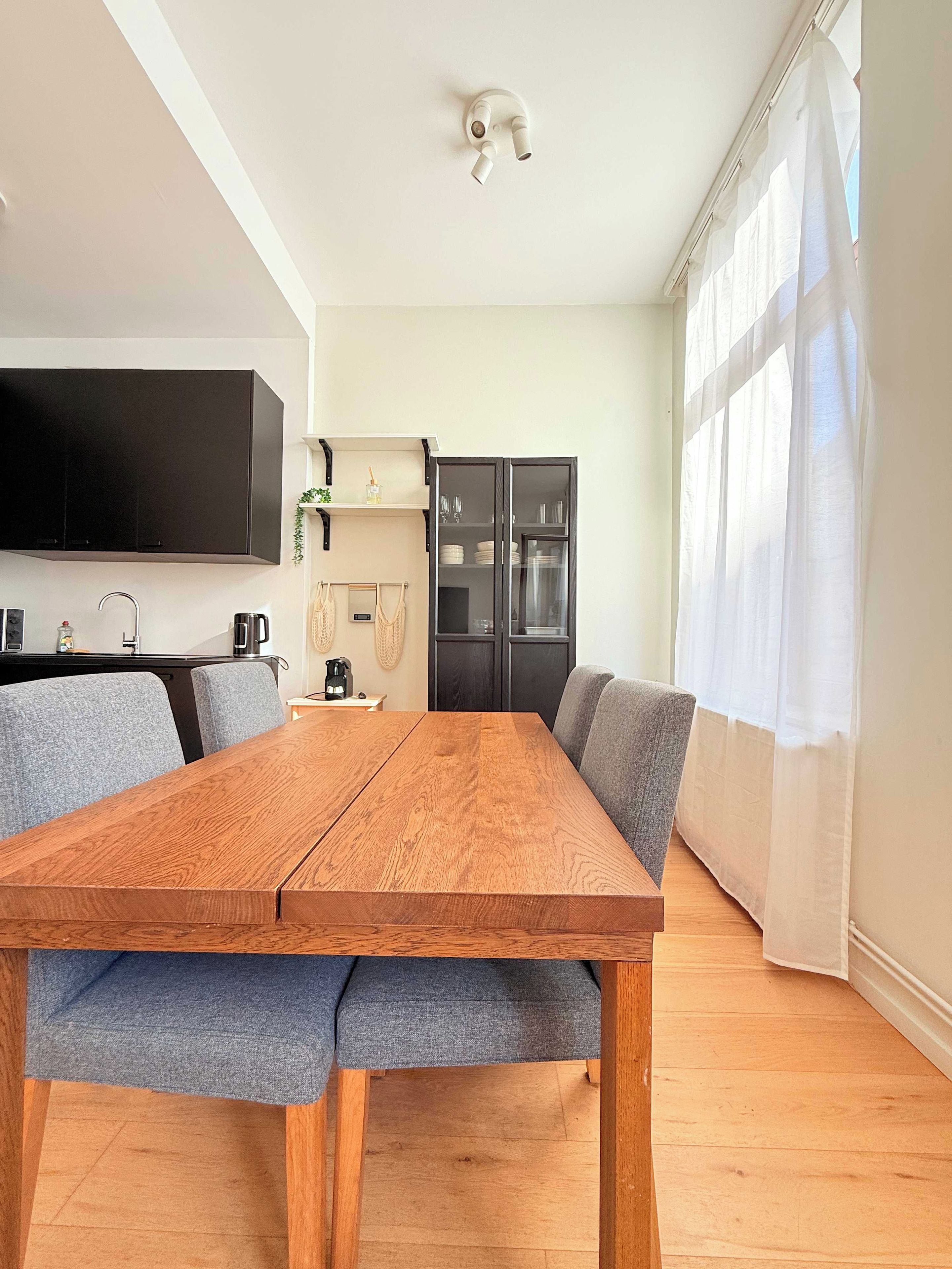 A modern kitchen with a built-in oven, a coffee machine, and a flat-screen TV mounted on the wall.