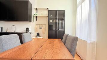 A modern kitchen with a built-in oven, a coffee machine, and a flat-screen TV mounted on the wall.