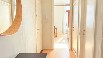 A hallway with a mirror, a desk, and a door leading to another room.