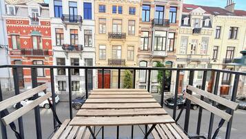 A balcony with wooden benches overlooking a row of colorful buildings with balconies.