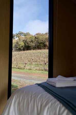 Una stanza con un letto, una finestra e vista su un vigneto.