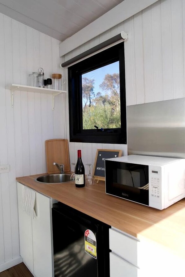 A compact kitchen with a sink, a microwave, and a wooden cutting board. - Spectacular Tiny House with Fantastic Sights in Ararat, Victoria (Ararat)