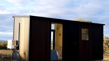 A mobile home with a large window, a door, and a small table with chairs.