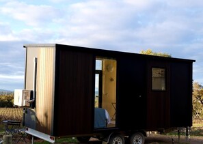 A mobile home with a large window, a door, and a small table with chairs.