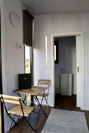 Una stanza con un tavolo e sedie in legno, un angolo cottura e una porta che dà su un'altra stanza.
