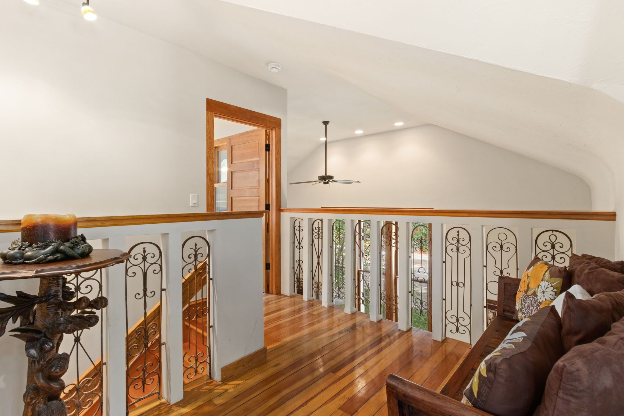 A spacious loft with a high ceiling, wooden flooring, and a ceiling fan.
