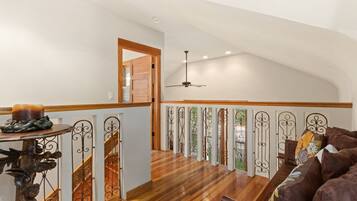 A spacious loft with a high ceiling, wooden flooring, and a ceiling fan.