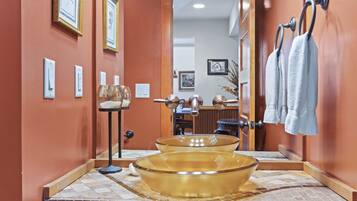A bathroom with a large glass bowl sink, a towel rack with towels, and a mirror reflecting the room.