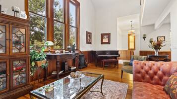 A spacious living room with a grand piano, a glass coffee table, and a leather sofa.