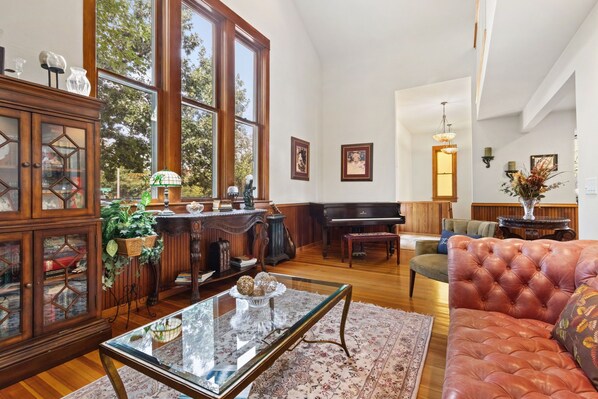 Uma sala de estar espaçosa com um piano de cauda, uma mesa de centro de vidro e um sofá de couro.