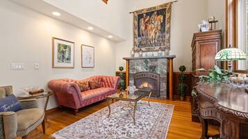 A living room with a fireplace, a red sofa, a coffee table, and a dining table with chairs.