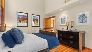 Una camera da letto con un letto, una cassettiera e opere d'arte appese alle pareti.