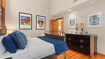 A bedroom with a bed, a dresser, and framed artwork on the walls.