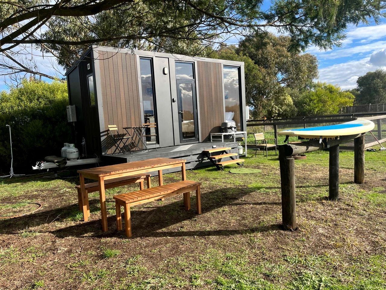 A modern outdoor area with a wooden bench, a picnic table, and a pool table.