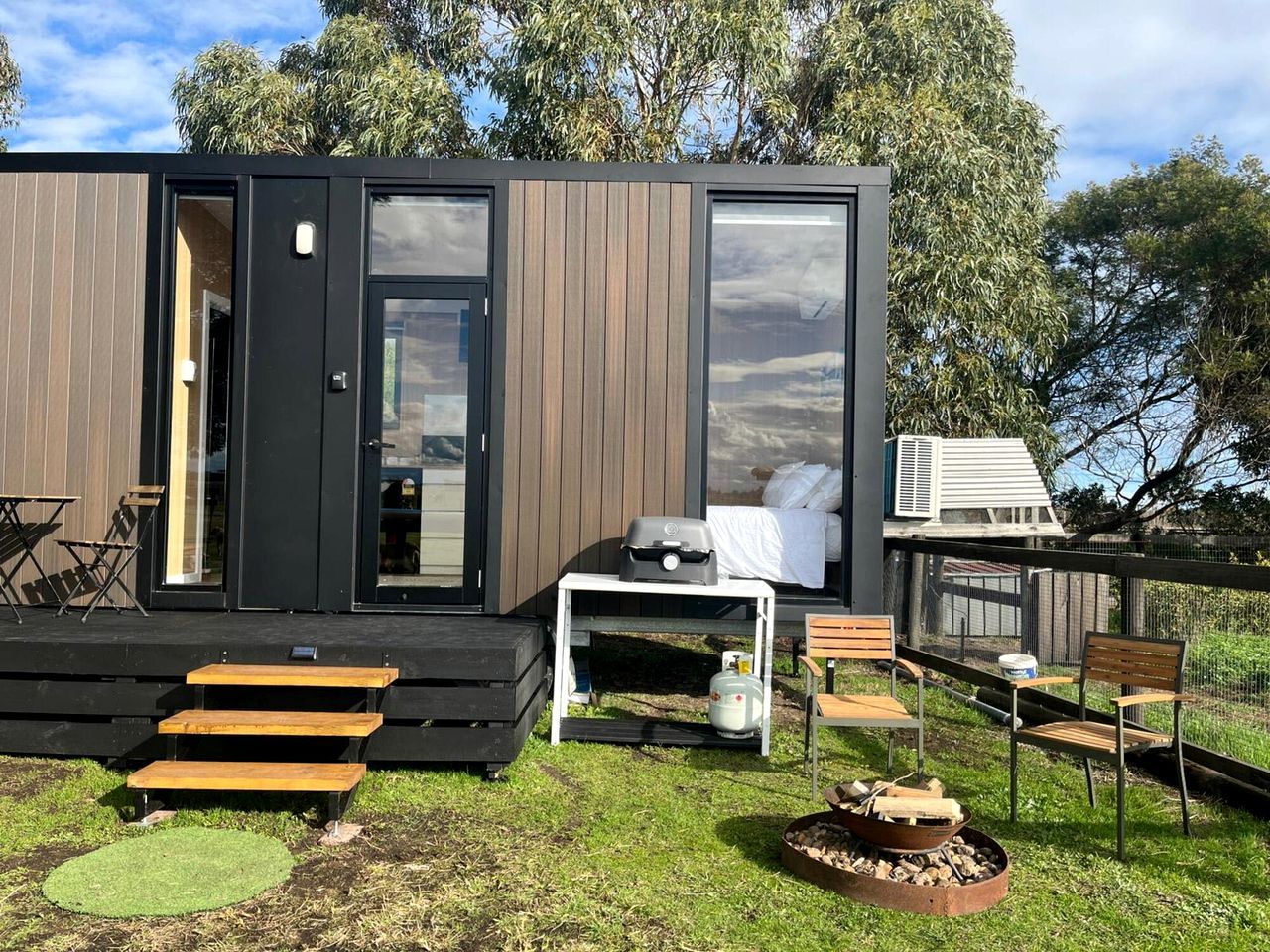 Une cabane moderne dotée d’une terrasse, d’un espace salon extérieur et d’un foyer.