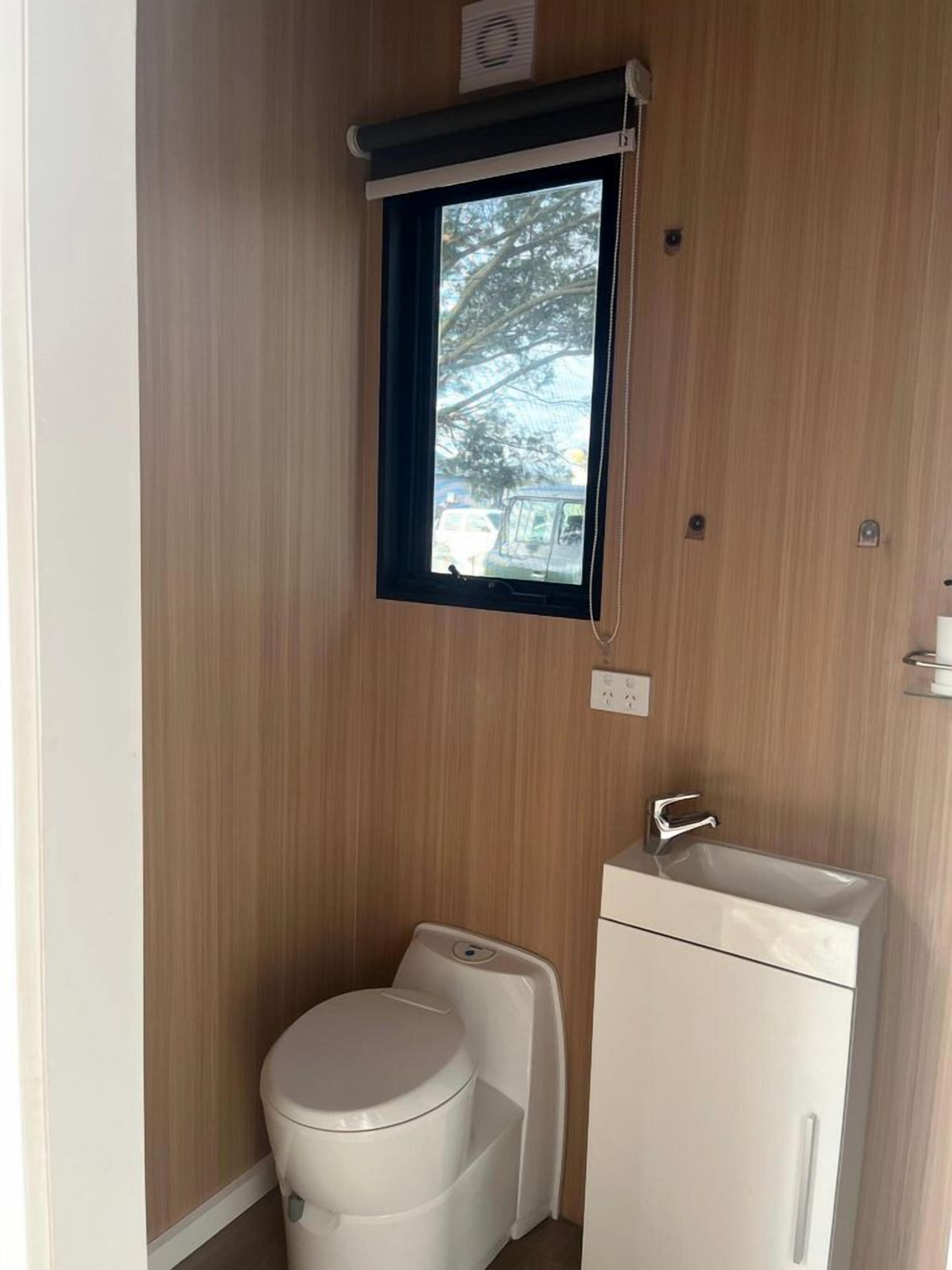 Une petite salle de bain comprenant des toilettes, un lavabo et une fenêtre.