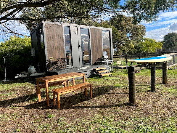A modern outdoor area with a wooden bench, a picnic table, and a pool table.