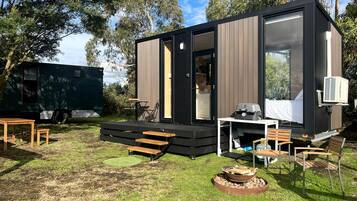 A modern, compact outdoor living space with a built-in table and chairs, a fire pit, and a deck area.