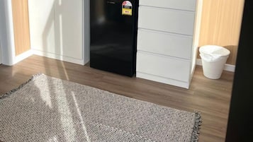A compact kitchen with a built-in microwave, a refrigerator, and a window with a view of greenery.
