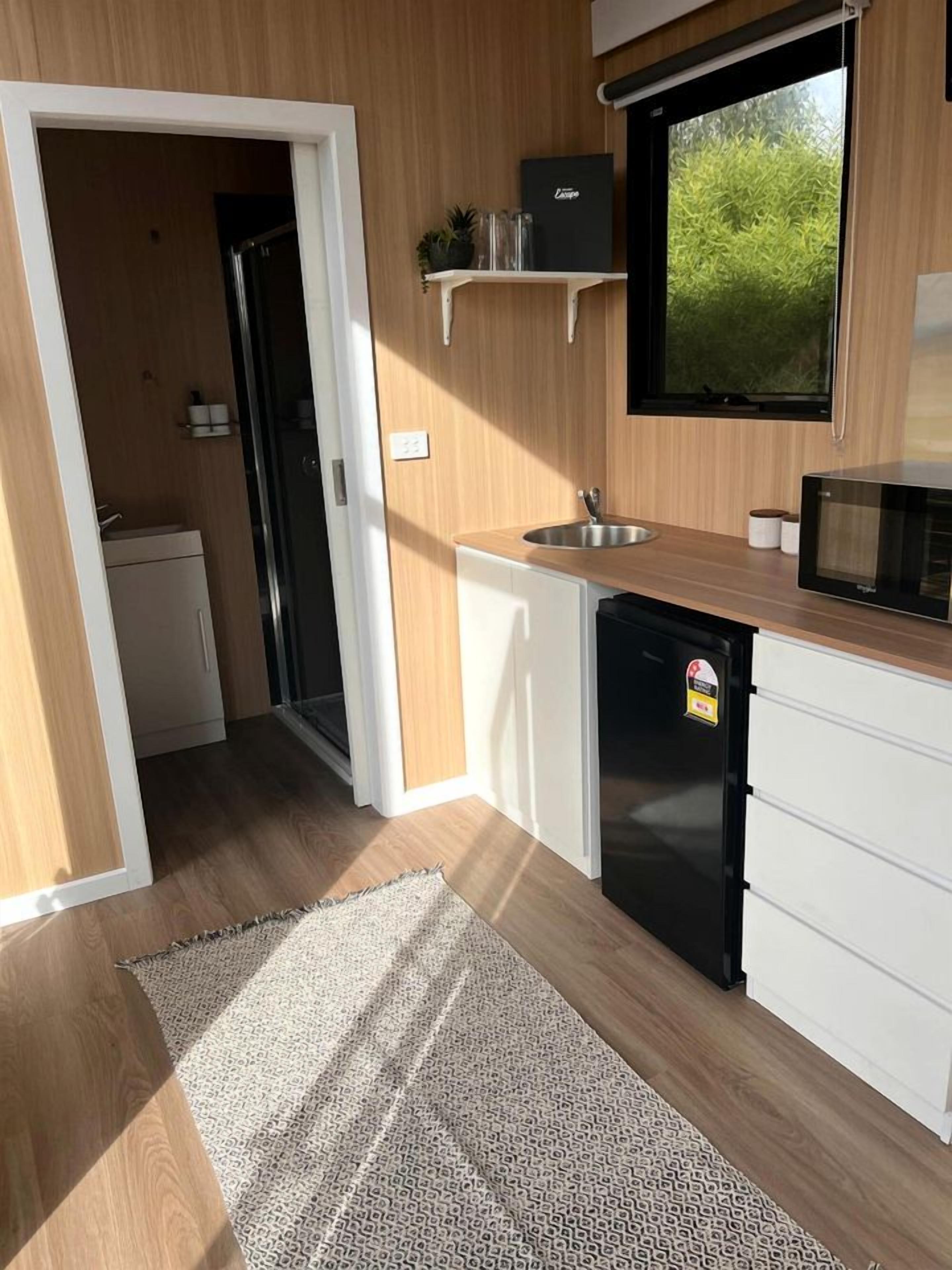 Cocina compacta con refrigerador, microondas y lavamanos.