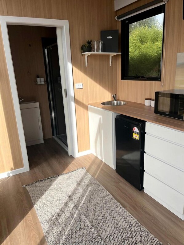 A compact kitchen with a refrigerator, microwave, and sink.