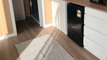 Kompakti keittiö, jossa on jääkaappi, mikroaaltouuni ja pesuallas.