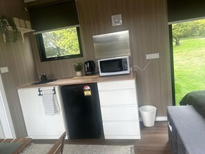 A compact kitchenette with a microwave, a small refrigerator, and a sink.