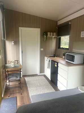 A compact kitchen with a microwave, sink, and a small refrigerator.