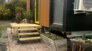 Un bâtiment moderne doté d’une terrasse en bois, d’une porte jaune et d’un mur noir.