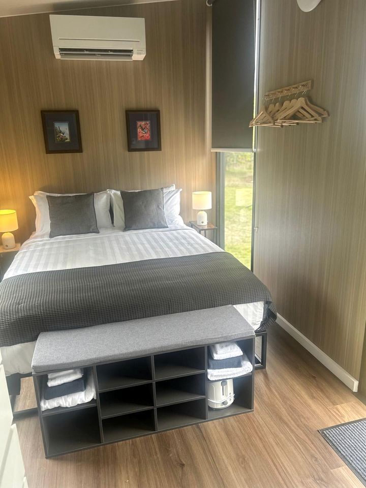 Une chambre à coucher comprenant un lit, des tables de chevet, un banc et une armoire.