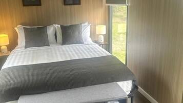 Une chambre à coucher comprenant un lit, des tables de chevet, un banc et une armoire.