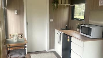 A compact kitchen with a microwave, sink, and a small refrigerator.