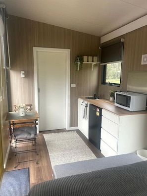 A compact kitchen with a microwave, sink, and a small refrigerator.