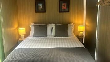 Une chambre d’hôtel comprenant un lit, des lampes de chevet, un bureau et des tiroirs de rangement.