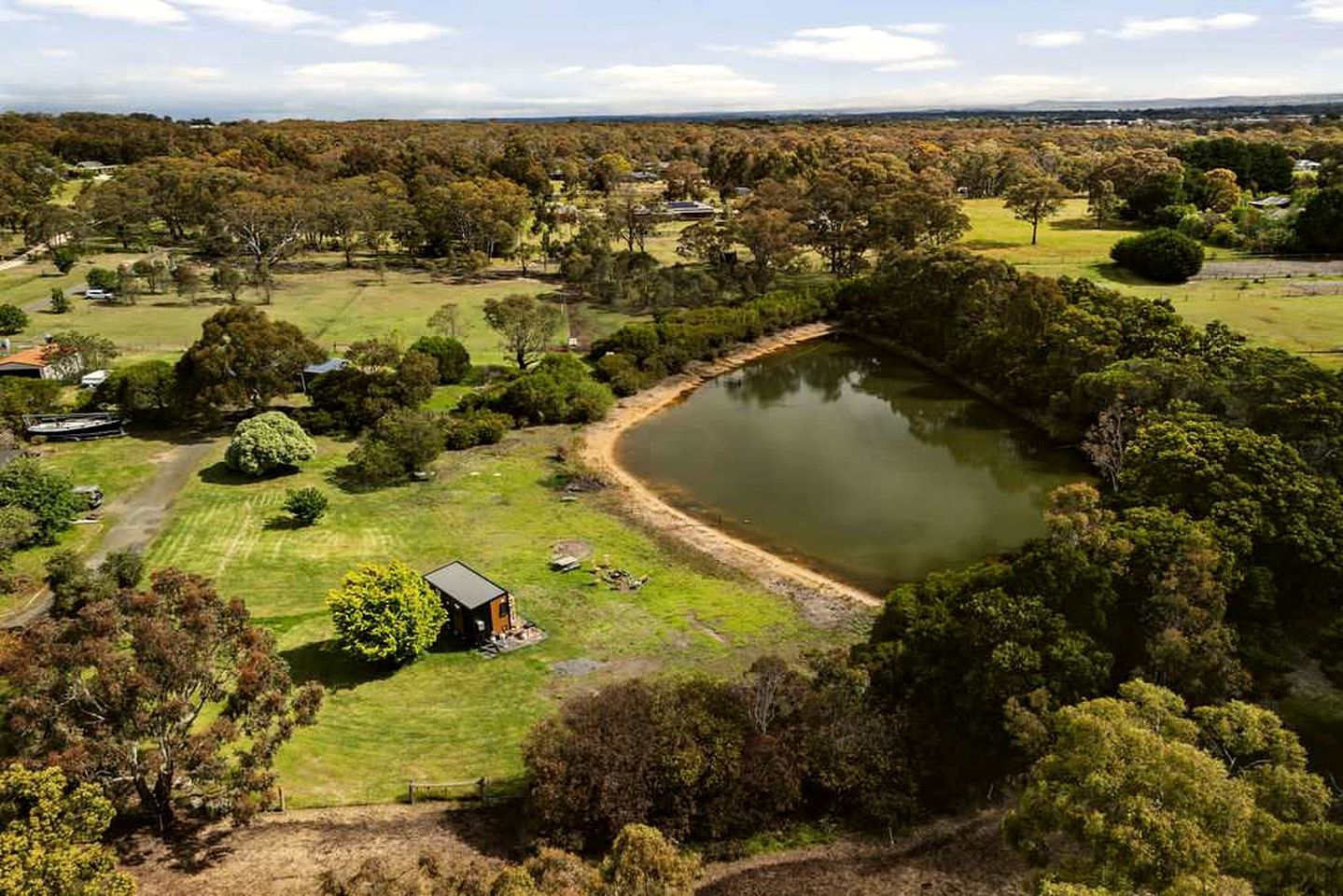A large body of water surrounded by trees and a small building.