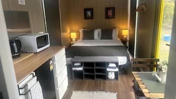 Une petite chambre comprenant un lit, des lampes de chevet, un four à micro-ondes et des tiroirs de rangement.